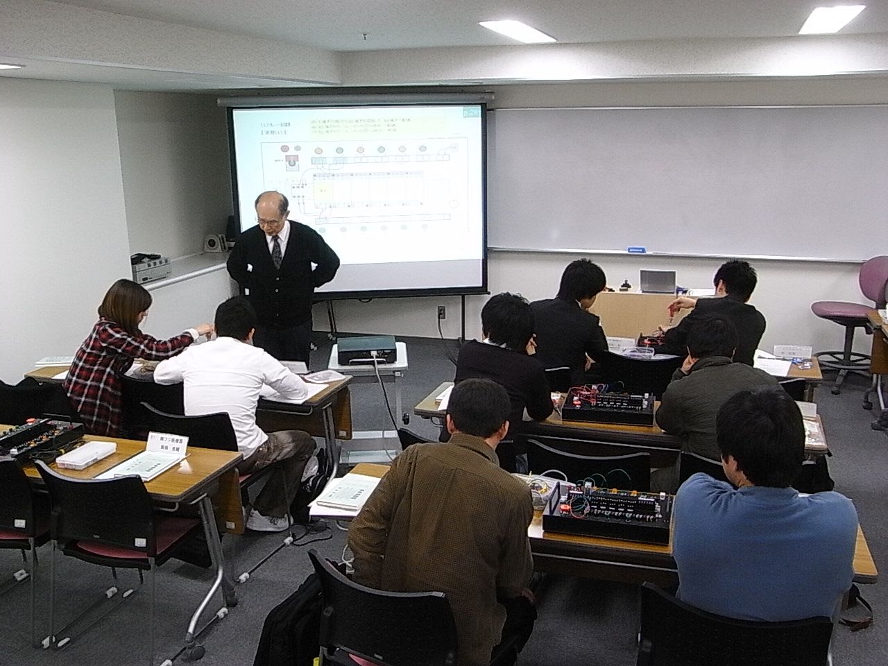 研修室で受講者に回路の説明をする代表
